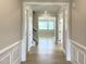 Inviting hallway with wood flooring and classic wainscoting leading to a sunlit living area and staircase at 82 N Stagecoach Dr, Wendell, NC 27591