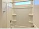 Shower-tub combo with bright white surround, built-in shelving, and transom window allowing for natural light at 82 N Stagecoach Dr, Wendell, NC 27591