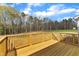A wooden deck with railings overlooks a scenic backyard and a treeline view under a bright sky at 9342 Turkey Way, Middlesex, NC 27557