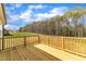 A wooden deck with railings overlooks a scenic backyard and a treeline view under a bright sky at 9342 Turkey Way, Middlesex, NC 27557