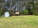 Large backyard featuring a fire pit, storage shed, playhouse, and mature trees at 100 Churchill Rd, Louisburg, NC 27549