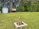 Large backyard featuring a fire pit, storage shed, playhouse, and mature trees at 100 Churchill Rd, Louisburg, NC 27549
