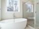 Modern bathroom featuring a luxurious soaking tub, walk-in shower, and nature views at 116 Bearwallow Forest Way, Wendell, NC 27591