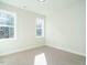 An empty bedroom with carpet floors and windows offering natural light and wooded view at 116 Bearwallow Forest Way, Wendell, NC 27591