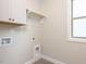 Bright laundry room featuring upper cabinets, hanging rod, tile flooring, and window for natural light at 116 Bearwallow Forest Way, Wendell, NC 27591