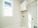 Bright laundry room featuring white cabinet, window, and laundry hookups at 116 Bearwallow Forest Way, Wendell, NC 27591