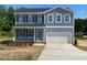 Charming two-story home featuring blue siding, a two-car garage, and a well-maintained front yard at 157 Grove Township Way, Angier, NC 27501