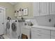 Well-organized laundry room with cabinets, sink, and modern washer and dryer at 1703 Happiness Hill Ln, Raleigh, NC 27614