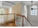 Bright staircase landing features a wooden banister, decorative rug, and beautiful arched windows, offering inviting natural light at 1703 Happiness Hill Ln, Raleigh, NC 27614
