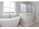 Bathroom featuring a freestanding soaking tub and glass shower with tile surround and a view to the outdoors at 1813 Bright Lantern Way, Wendell, NC 27591