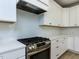 Close-up of a kitchen featuring white cabinets, a subway tile backsplash, and stainless steel oven range at 1813 Bright Lantern Way, Wendell, NC 27591