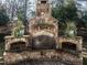 Close-up of a stone outdoor fireplace with wood storage and decorative plants at 2900 Glenanneve Pl, Raleigh, NC 27608