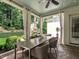 Covered patio with a dining table and chairs, offering a view of a stone fireplace and landscaped backyard at 2900 Glenanneve Pl, Raleigh, NC 27608