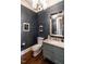 Stylish powder room featuring wallpaper, modern lighting, vanity, mirror, and hardwood floors at 2900 Glenanneve Pl, Raleigh, NC 27608