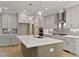 Open kitchen with island, stainless appliances, gray cabinets, quartz countertops, and modern pendant lights at 3925 Cedar Knolls Dr, Youngsville, NC 27596