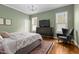 This bedroom features green walls, hardwood floors, a king size bed, and a large dresser with a television at 4201 Henderson Pl, Pittsboro, NC 27312