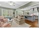 An open living area with a comfortable seating arrangement, light-filled windows, and an open view of the kitchen at 4201 Henderson Pl, Pittsboro, NC 27312