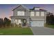 Two-story home with gray siding, white trim, and a two-car garage at dusk at Tbd Charlotte Knoll St # 9, Zebulon, NC 27597