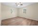 Sunlit bedroom showcasing gleaming hardwood floors, a ceiling fan, and two windows at 1219 Carlton Ave, Burlington, NC 27217