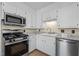 Close-up of a kitchen with stainless steel appliances, granite counters, and white cabinetry at 1219 Carlton Ave, Burlington, NC 27217