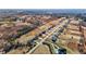 High-angle aerial view of a neighborhood's layout, with rows of similar houses bordered by a natural, undeveloped landscape and a small pond at 2995 Faucette Ln, Burlington, NC 27217