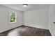 Empty bedroom with wood look flooring, neutral paint, a window with a tree view and a ceiling light at 621 Shepard School Rd, Zebulon, NC 27597