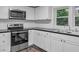 White kitchen featuring stainless steel appliances, black countertops, and a window over the sink at 621 Shepard School Rd, Zebulon, NC 27597