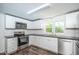 Renovated kitchen with white cabinets, stainless steel appliances, and dark countertops at 621 Shepard School Rd, Zebulon, NC 27597