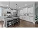 Spacious kitchen featuring an island with barstool seating, white cabinets, black countertops and stainless steel appliances at 101 Pointe Park Cir, Holly Springs, NC 27540