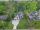 Aerial view of a landscaped home with a long driveway and a yard surrounded by lush trees at 1304 Ivy Ln, Raleigh, NC 27609