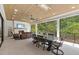 Covered patio offers a fireplace, ceiling fan, tv, and an outdoor dining area overlooking the lush greenery at 1304 Ivy Ln, Raleigh, NC 27609