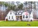 Two-story farmhouse with white siding, brown doors, and a landscaped lawn at 257 Rawhide Dr, Louisburg, NC 27549