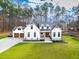 Stunning farmhouse exterior boasts a white exterior, large windows, and a 3-car garage at 257 Rawhide Dr, Louisburg, NC 27549