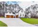 White farmhouse with three-car garage, stone accents, and a long driveway at 257 Rawhide Dr, Louisburg, NC 27549