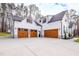 Three-car garage with brown doors and white siding, attached to a farmhouse at 257 Rawhide Dr, Louisburg, NC 27549