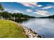 Peaceful lakefront view with a grassy area and stone retaining wall at 257 Rawhide Dr, Louisburg, NC 27549