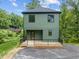 Green house exterior with deck and black railing, nestled among lush greenery at 100 A Masondale Ave, Durham, NC 27707