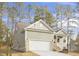 Side view of a one-story home with light green siding, attached garage, and freshly poured driveway surrounded by tall trees at 100 Sequoia Dr # 2387, Louisburg, NC 27549