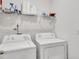 Bright laundry room with washer, dryer, storage shelf, and white walls at 108 Bonnie Girl Ct, Lillington, NC 27546