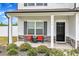 Front porch featuring two chairs, a table, a black door, stone accents and landscaping at 108 Bonnie Girl Ct, Lillington, NC 27546