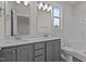 This bathroom features double sinks, gray cabinetry, and a bright window with a view of trees and a blue sky at 150 Brookhaven Dr, Spring Hope, NC 27882