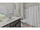 Clean bathroom with dark vanity, shower with white curtain and neutral walls at 2001 Bunnfield Dr, Zebulon, NC 27597