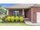 Charming brick home features a cozy front porch with vibrant landscaping and stylish seating at 2001 Bunnfield Dr, Zebulon, NC 27597