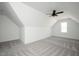 An attic bedroom with angled walls and a single window has neutral colored carpet and a ceiling fan at 321 Bud Wall Rd, Youngsville, NC 27596