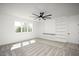 Bright bedroom with a modern ceiling fan, built-in shelving, a large window and neutral colored carpet at 321 Bud Wall Rd, Youngsville, NC 27596