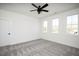 A bright bedroom features neutral colored carpet, white walls, three windows and a ceiling fan at 321 Bud Wall Rd, Youngsville, NC 27596