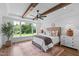 Light-filled bedroom with wood beam ceiling, area rug, and large windows overlooking a green yard at 321 Bud Wall Rd, Youngsville, NC 27596