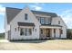 A bright modern farmhouse with white siding, brick accents, a covered porch, and manicured landscaping at 321 Bud Wall Rd, Youngsville, NC 27596