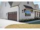 Angle view of a house with a wooden garage door, wooden awning over window, and exterior light fixtures at 321 Bud Wall Rd, Youngsville, NC 27596