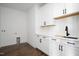 Well-lit laundry room boasts white cabinets, a white countertop, a sleek black faucet, and wood-look floors at 321 Bud Wall Rd, Youngsville, NC 27596
